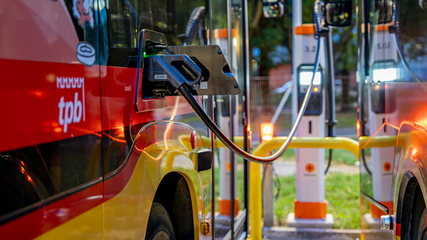 Electric bus charging at a station, with multiple chargers lined up.