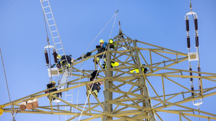 Technicians on a high-voltage pylon replace insulators